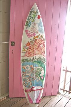 a surfboard is on display in front of a pink door with words written all over it