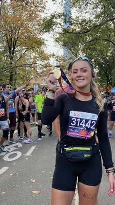 a woman is holding up her medal in the middle of a marathon