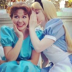 two women dressed as disney characters sitting next to each other on a bed and one is touching her face