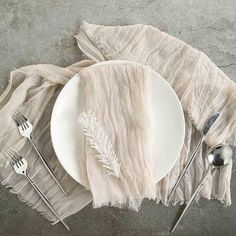 a white plate topped with silverware next to a napkin and spoons on top of a table