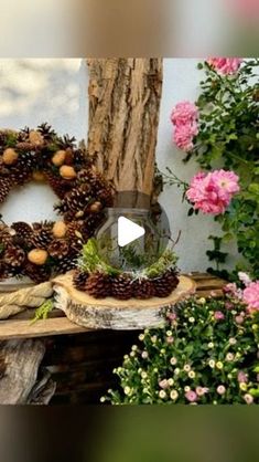 a wreath with pinecones and other decorations on top of a wooden table surrounded by flowers