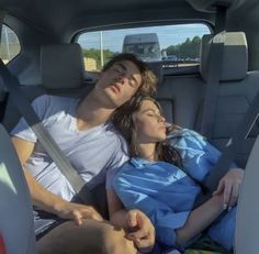 a man and woman laying in the back seat of a car with their eyes closed