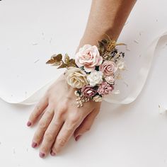 a woman's hand with flowers and leaves on her wrist wearing a white bracelet