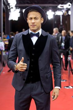 a man in a tuxedo and bow tie giving the thumbs up at an event