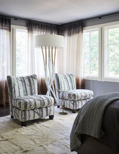 a bedroom with two chairs and a lamp in the corner, along with a rug on the floor