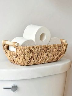 a wicker basket on top of a toilet with rolls of toilet paper in it