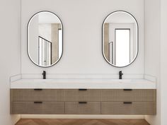 two round mirrors on the wall above a sink in a white room with wood flooring