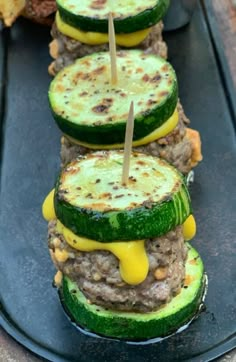 cucumber sandwiches are arranged on a black plate with toothpicks in them