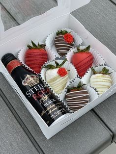 a box filled with chocolate covered strawberries next to a bottle of wine on top of a table