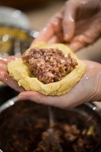 two hands are holding food in the shape of a heart on top of a bun