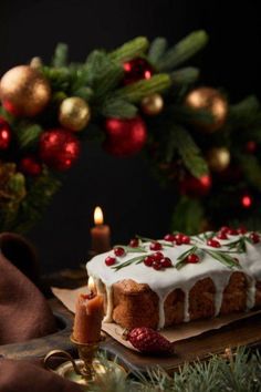 a cake with white frosting and cranberries on it next to a candle