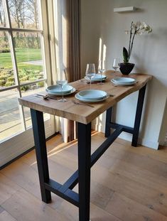 a wooden table with plates and glasses on it in front of a sliding glass door