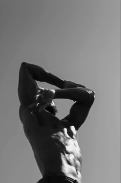 black and white photograph of a man with no shirt holding his hands behind his head