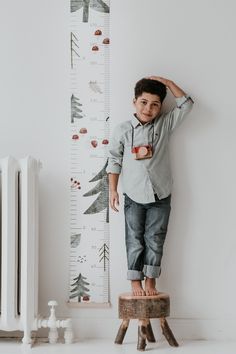 a young boy standing on a stool next to a growth chart