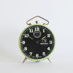 an alarm clock sitting on top of a white table next to a black and green one