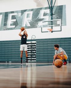 two young men playing basketball on an indoor court