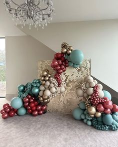 a large sculpture made out of balloons and other items in a room with a chandelier