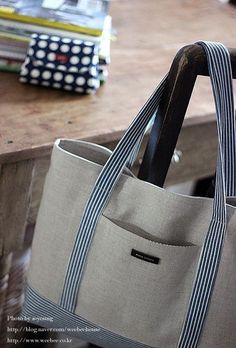 a gray bag sitting on top of a wooden table next to a pile of books