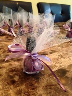 a vase filled with purple flowers on top of a marble table covered in tulle