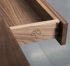 a close up of a wooden table with a drawer on it's side,