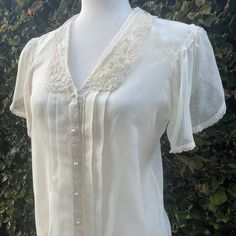 "Dainty Jessica McClintock light and breezy blouse with beautiful lace detail.  Features a split scalloped sleeve trimmed in lace at the hem and shoulder that falls gracefully over the upper arm.  An elegant scalloped embroidered lace collar graces the neck.  Faux pearl buttons grace the front adorned by 2 pleats trimmed in lace on either side.  The cotton is light and breezy and is sure to be a wardrobe favorite. Circa:  1970's Designer:  Gunnies, Jessica's Gunnies of San Francisco Size:  Best Vintage Lace Top With Lace Trim For Formal Events, Classic Blouse With Lace Sleeves For Daywear, Summer Formal Lace Top With Lace Collar, Formal Lace Collar Top For Summer, Formal Summer Lace Collar Top, Elegant Flowy Lace Tops, Classic Short Sleeve Blouse With Lace Trim, Classic Fitted Blouse With Lace Sleeves, Fitted Classic Blouse With Lace Sleeves