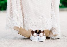 a woman in white dress and gold shoes standing on the ground with her legs crossed