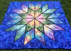 a blue quilt on the grass with a large flower in the center and many smaller flowers at the bottom