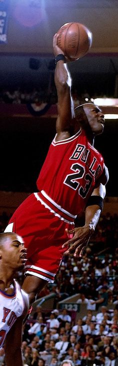 a basketball player jumping up into the air with a ball in his hand and people watching from the stands