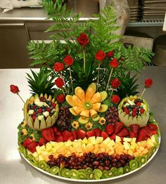 a platter filled with fruit and flowers on top of a table