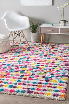 a colorful rug in the corner of a room with a white chair and potted plant