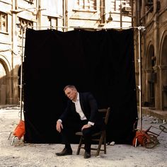 a man sitting on a chair in front of a black backdrop