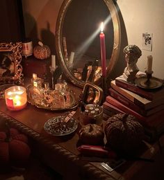 a table topped with books and candles next to a mirror on top of a wooden table