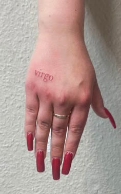 a woman's hand with a small tattoo on her left thumb and the word vigo written in red ink