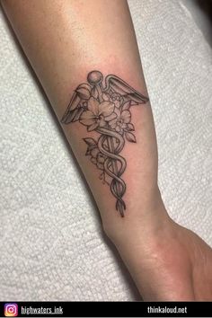 a tattoo on the arm of a woman with flowers and cadus in black ink