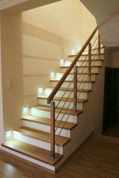 an empty room with some stairs and lights on the wall next to it is lit up by recessed lighting