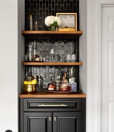 a black cabinet with lots of glasses and bottles on it in the corner of a room