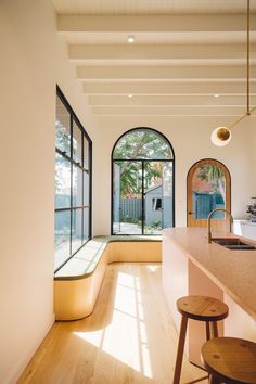 a kitchen with an island counter and stools in front of the window that looks out onto the backyard