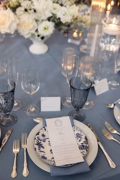 the table is set with silverware and blue linens, which are accented with white flowers