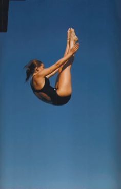 a woman is in the air doing a trick on a surfboard with her feet up