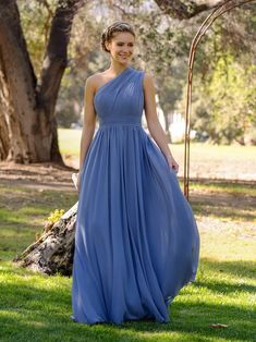 a woman in a long blue dress standing on the grass