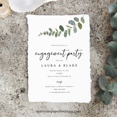 an engagement party card with greenery on it next to shells and seashells