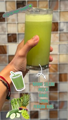 a hand holding a glass filled with green liquid