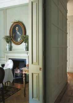 an open door leading to a living room with a fireplace and painting on the wall