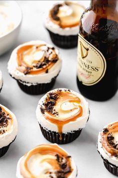 cupcakes with frosting and caramel on them next to a bottle of beer