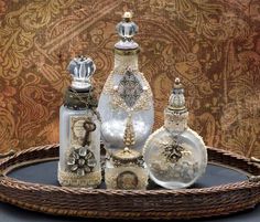 three glass bottles sitting on top of a wicker tray with other items in it