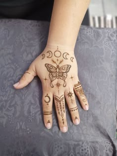 a woman's hand with hennap and moon tattoos on her left hand