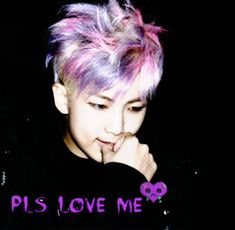 a person with pink and purple hair is looking down at his hand while wearing a black shirt