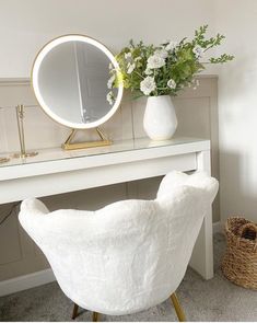 a white chair sitting in front of a table with a mirror on top of it