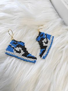 two pairs of blue and black beaded earrings sitting on top of a white furry surface