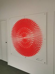 a white wall with a red circular artwork on it